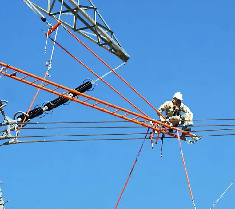 Eletricista com capacete e equipamento de segurança trabalhando em linha de alta tensão, com escada isolante